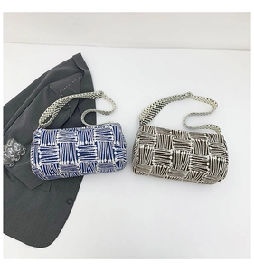 Close-up of blue and brown woven cylinder tote bags with wide patterned straps on white desk