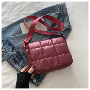 Close-up of maroon quilted crossbody bag featuring glossy fabric and adjustable wide strap