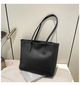 Detail of the black leather tote bag showing the smooth texture and large capacity size