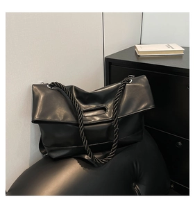 Detailed close-up of a soft black leather tote featuring a thick woven rope shoulder strap