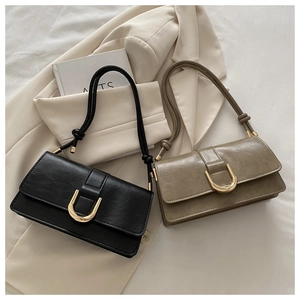 Minimalist square flap bag detail featuring gold U-shaped buckle and knotted strap