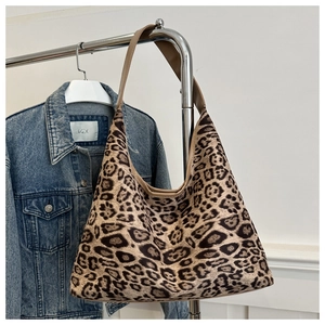 Detail of leopard print tote bag with brown faux leather strap on a metal hanger