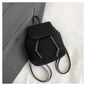Detail of a textured wool backpack with dark brown PU leather straps on a grey blazer