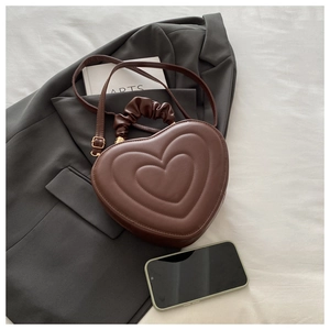 Détail de sac marron en forme de cœur avec motifs gaufrés et poignée froncée