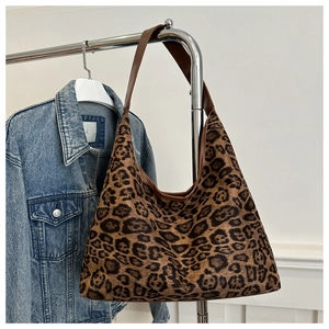 Close-up of leopard print hobo bag texture and wide brown strap with denim background