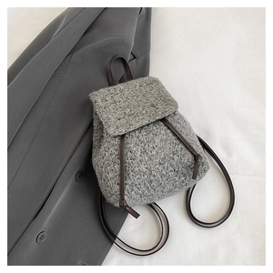 Detail of grey tweed backpack with drawstring closure and slim brown leather straps