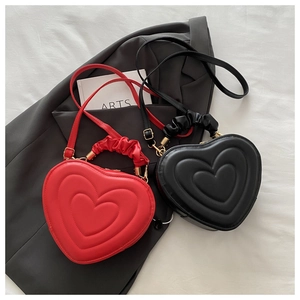 Détail de sacs en PU rouge et noir en forme de cœur avec anses froncées et boucles dorées