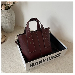 Detail of burgundy lychee leather tote bag with gold rivets and fine stitching details