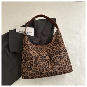 Close-up of leopard print tote bag with brown leather handles and textured fabric