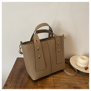 Close-up of brown litchi pattern leather tote with golden rivets on a wooden table