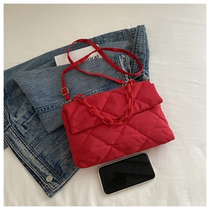 Détail du sac à bandoulière matelassé rouge avec chaîne sur une scène de fond blanc
