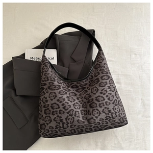 Detail of grey leopard print tote bag with black wide strap on casual blazer