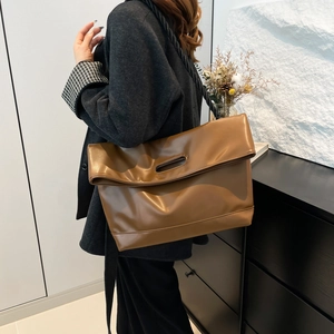 Brown minimalist leather tote bag with unique hollow handle and woven shoulder strap