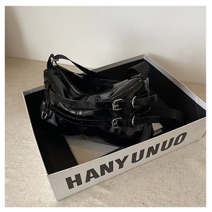 Detail of black glossy patent leather shoulder bag with metal buckle belt decorations