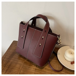 Detailed view of burgundy lychee leather bucket bag with white contrast stitching