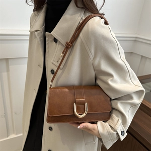Brown leather crossbody bag for women featuring a gold U-shaped buckle and knot strap detail