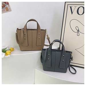 Detail of khaki and navy bucket bags with lychee leather texture and metal rivets