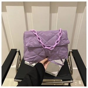 Pochette matelassée violette chic avec chaîne sur une chaise en cuir noir classique