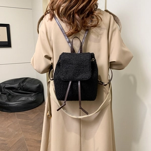Women's black faux fur backpack with brown leather straps shown on model back