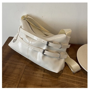 Close-up of cream glossy PU shoulder bag featuring dual strap buckles and fabric strap