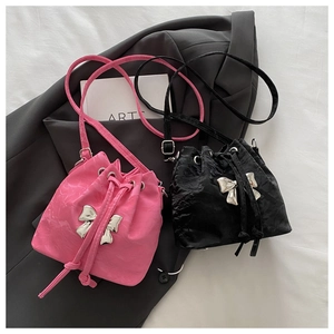 Close-up of mini drawstring bucket bags in pink and black with silver butterfly detail