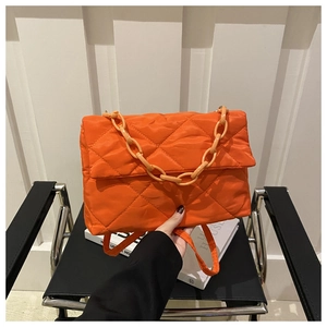 Détail du sac enveloppe matelassé orange avec chaîne décorative et texture en nylon