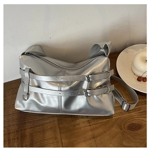 Close-up of metallic silver PU leather bag featuring decorative buckle straps and texture