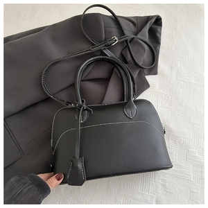 Detail of black shell bag with white contrast stitching and adjustable shoulder strap