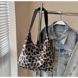 Detail of leopard print plush tote bag hanging on a metal hanger with denim jacket