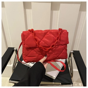 Gros plan d'un sac bandoulière matelassé rouge avec poignée chaîne en plastique épais