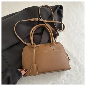 Detail of vintage brown shell bag with white contrast stitching and circular handles