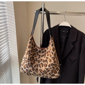 Detail of plush leopard print faux fur texture and black wide leather shoulder strap