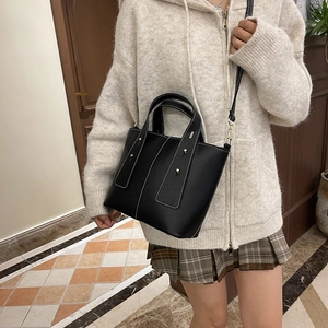 Black pebbled leather tote bag with white contrast stitching and gold buckle details
