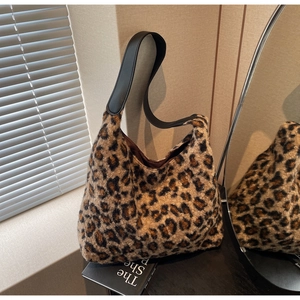 Close-up of leopard print plush fabric texture and black leather strap on tote bag