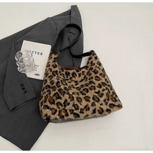 Detail of plush leopard print shoulder bag with black leather strap on a chic studio set