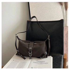 Detail of dark brown fashion bag with silver buckle on a minimalist black leather chair