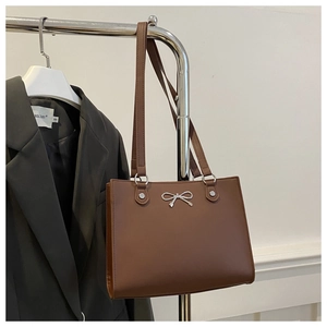 Detail of the silver butterfly bow accent on this brown structured tote shoulder bag