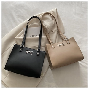 Detailed view of black and khaki tote bags with silver butterfly ornament and long straps