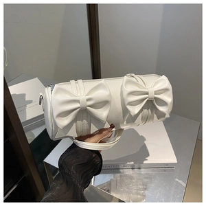 Close-up of white cylindrical bag with dual bow details and premium matte leather texture