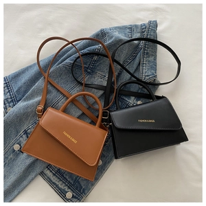Detail view of brown and black mini crossbody bags with gold lettering and denim background