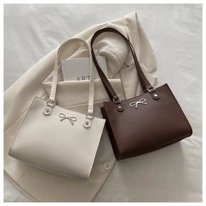 Close-up of cream and brown leather tote bags with elegant silver butterfly buckles