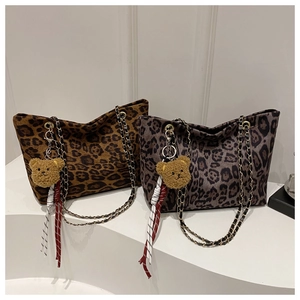 Detail of leopard print tote bags with metal chain straps and plush bear charms