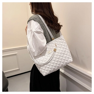White quilted tote bag with metal lettering plate shown on model in elegant interior