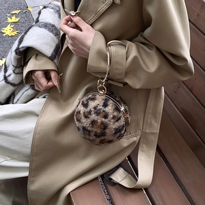 Leopard print spherical clutch bag with gold chain strap shown in an autumn street setting