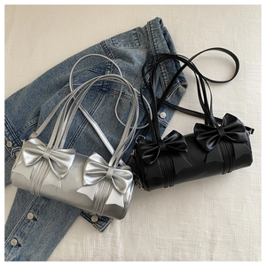 Detail of silver and black cylinder bags with large bow accents on white texture