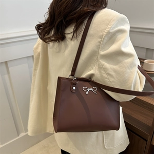 Vintage brown shoulder bag with silver butterfly charm shown on a model in casual style