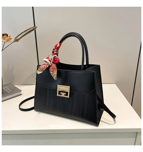 Detail of black leather handbag with golden G-lock, decorative scarf, and shoulder strap