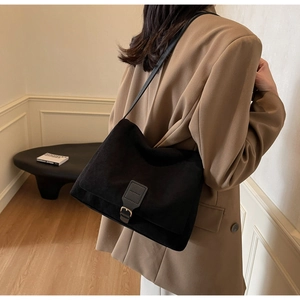 Detail of matte black commuter shoulder bag with silver buckle and magnetic flap