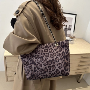 Winter leopard print tote bag with black and gold chain strap shown on a model