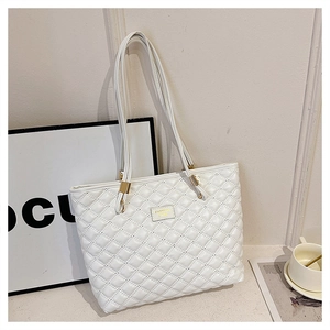 Close-up of a white quilted tote bag with golden metal logo and coffee cup decoration